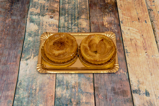 apple tartlets with puff pastry, apricot jam and cinnamon on wooden table