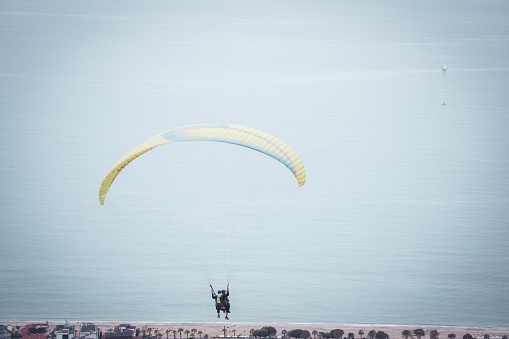 Paragliding in the sky. Paraglider  flying over the sea with blue water and mountains