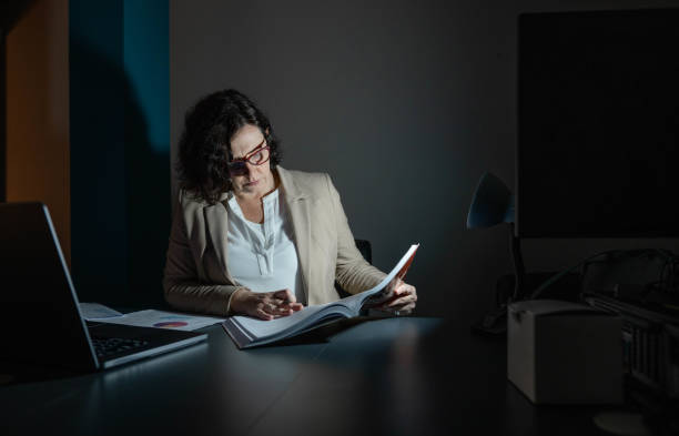 istock Mature businesswoman reading documents while working late in a dark office 1482662617