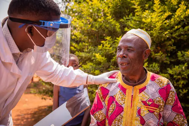 An African doctor talks to an elderly patient during a medical examination.