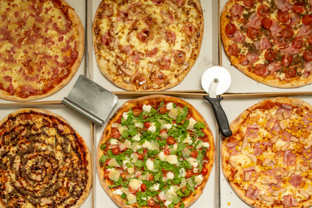 istock Delicious assorted freshly baked Pizzas together with pizza cutters in home delivery boxes 1482666122