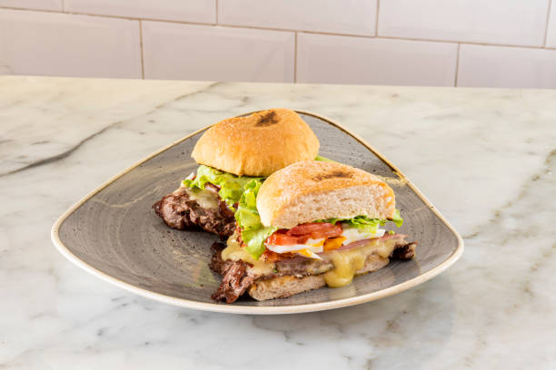 istock Grilled lamb and smoked bacon sandwich with melted cheese, chopped boiled egg, iceberg lettuce and tomato slices on a large marble table 1482666248