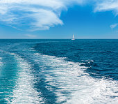 istock Trace tail of speed boat or ferry on water surface in the sea and white sailing vessel in far. Natural and vacation background. 1482666515