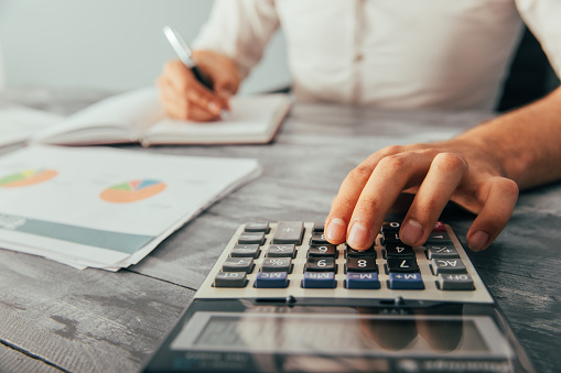 A man writes in a notebook and counts in front of statistics on the table