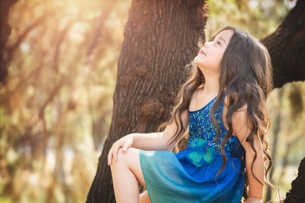 beautiful happy little girl playing in the park in blue dress without shoes laughing screaming with happiness in family enjoying children's day stock photo