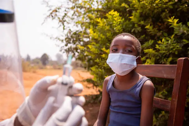 A doctor is about to vaccinate a child, close up on the child wearing a surgical mask