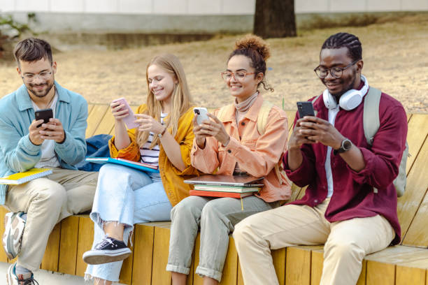 istock Group of cheerful students sitting together and using their smart phones 1482680457