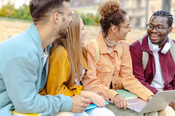 istock Hanging out on campus. Young group of students using laptop 1482680496