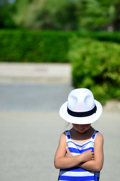 Brown-haired girl of seven wearing a striped blouse and jaunty hat.