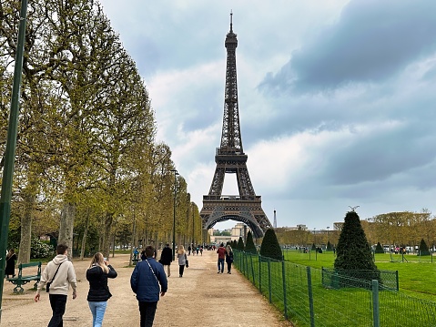 Paris, France - April 10 2023: a tourist is walking in the champ de mars park at the foot of the eiffel tower landmark