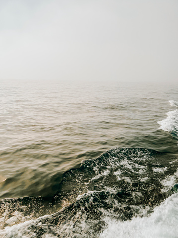 A misty fog settles over Lake Superior. Point of view from a ferry boat gliding through the deep waters creating waves and wake in its path. Located between Isle Royale and Copper Harbor in the remote Upper Peninsula of Michigan.