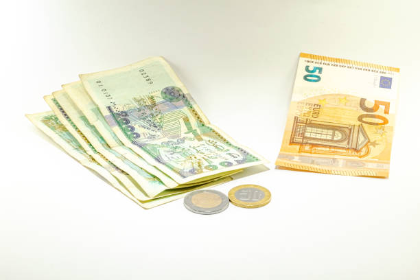Fifty Euros bill and five bills of two thousand Algerian dinars with a coin of one hundred and a coin of fifty dinars on white background.