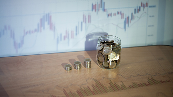 Coin saving jar and finance chart concept photo