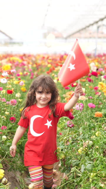 4K video of preschooler girl holding Turkish Flag in flower garden
