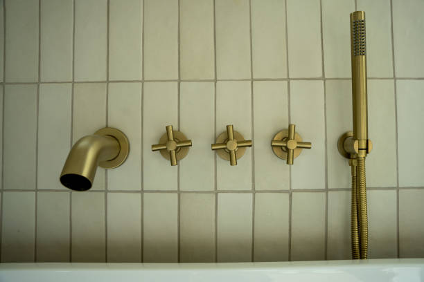istock Luxurious brass bath faucet with a removable hand water sprayer on a tiled wall . 1482698026