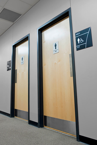 Two wooden public bathroom doors with signs.