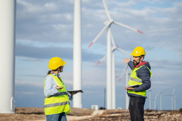 istock Pregnant wind energy engineer working in team at wind farm. 1482703420