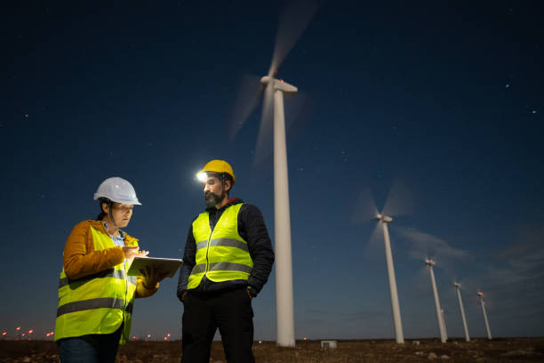 istock Pregnant wind engineer working in team at night in wind farm. 1482703435