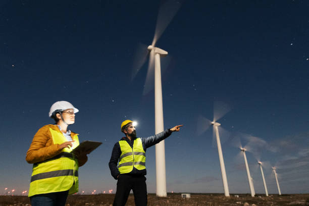 istock Pregnant wind engineer working in team at night in wind farm. 1482703437
