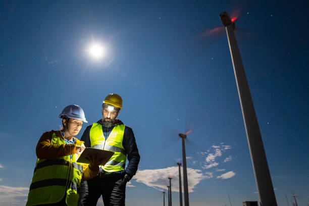 istock Pregnant wind engineer working in team at night in wind farm. 1482703438