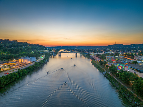 An aerial view of the sun setting behind boaters on the river during the Charleston Sternwheel Regatta.