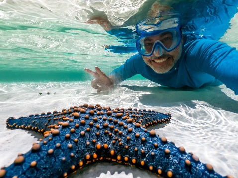 Adult man taking a selfie with a beautiful blue sea star
