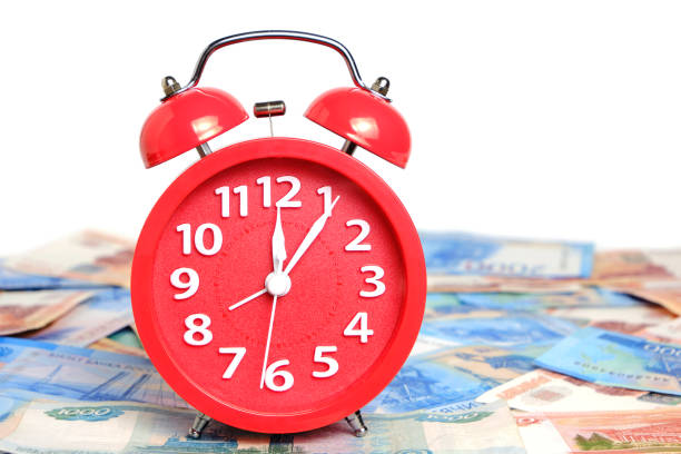 istock Russian rubles and red alarm clock white background.Time Russian ruble. 1482710674