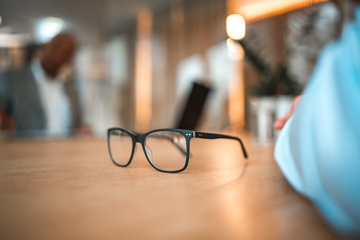 Close up on eyeglasses on a desk in a modern office.
