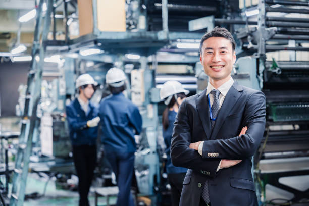 White-collar man crossing his arms at the factory stock photo