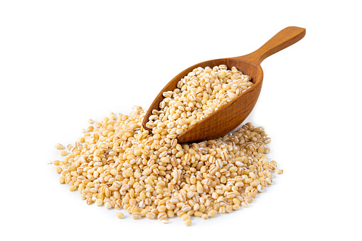 pearl barley in wooden scoop isolated on white background