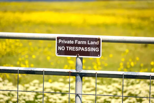 Private Farm Land No Trespassing sign posted on a wire fence/