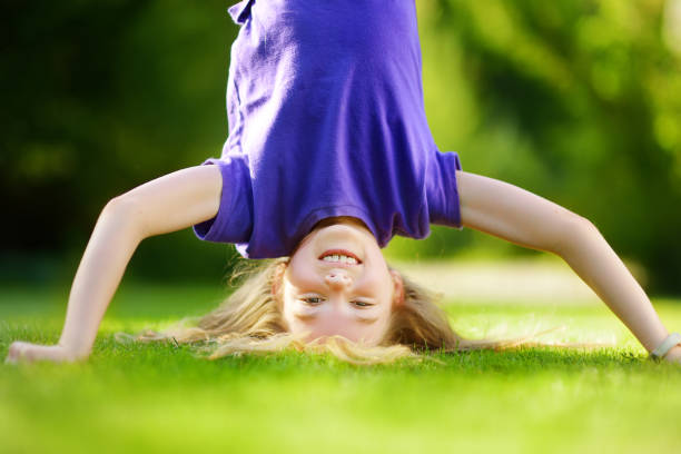 istock Happy young child playing head over heels on green grass in spring park 1482721999