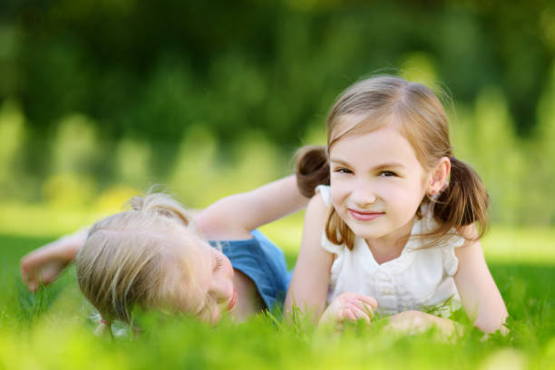 istock Two cute little sisters having fun together on the grass on summer day 1482722069