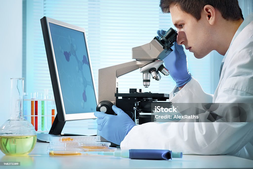 laboratory technician at work scientist looking into microscope at the lab White People Stock Photo
