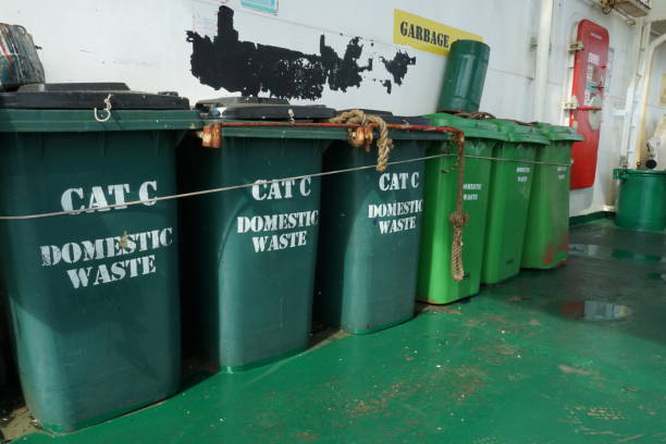 istock Green plastic garbage bins for domestic waste, category C, firmly behind superstructure on the stern part of cargo container vessel. 1482723069