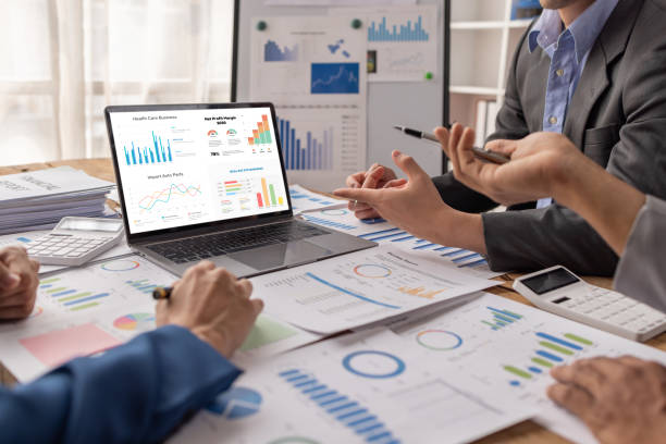 groupe de gens d’affaires confiants pointent vers des graphiques et des tableaux pour analyser les données du marché, le bilan, le compte, le bénéfice net pour planifier de nouvelles stratégies de vente afin d’augmenter la capacité de production. - étude de marché photos et images de collection