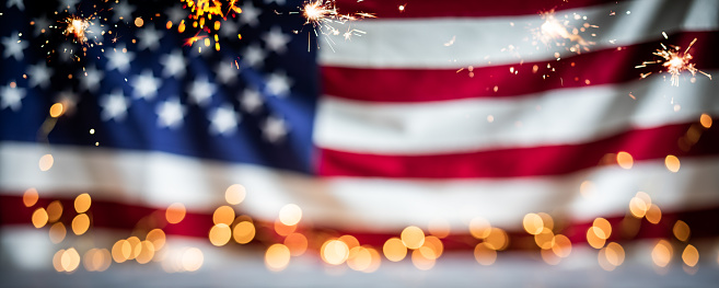Defocused US flag with bokeh lights and sparklers. Fourth of July Independence Day background.