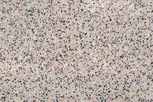 istock Grainy kitchen countertop top view. Surface of spotted empty table, abstract background with small black and white stones, rough material, grain light brown pattern. 1482745454