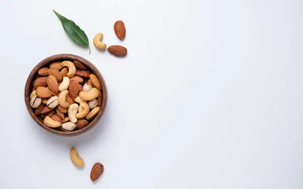 nuts almonds, pistachio and cashews are placed in a wooden bowl  on a light blue background. Top view, flat lay and copy space