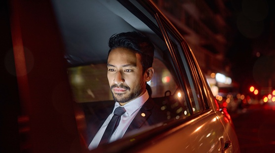 Night, travel and business man in car relaxing, commuting and traveling after working. Transport, road and young male professional, passenger or businessman sitting in vehicle, motor or taxi in city.