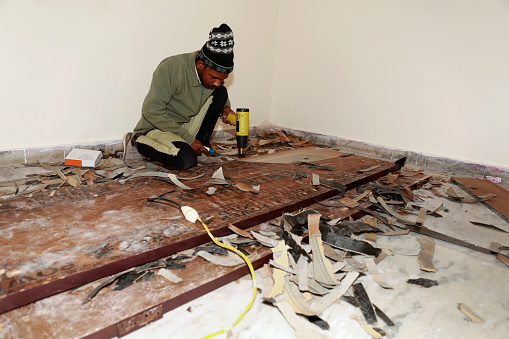 Carpenter removing old varnish from wood using scraper and heat gun at his workshop portrait Indoor.