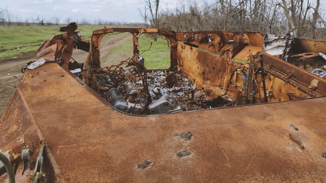 Russian tank or bmp destroyed by the Ukrainian military during the invasion of Ukraine. The remains of a blown up Russian tank in the Kherson region, Ukraine 2022 - 2023. The tank is covered with rust and begins to overgrow with plants.