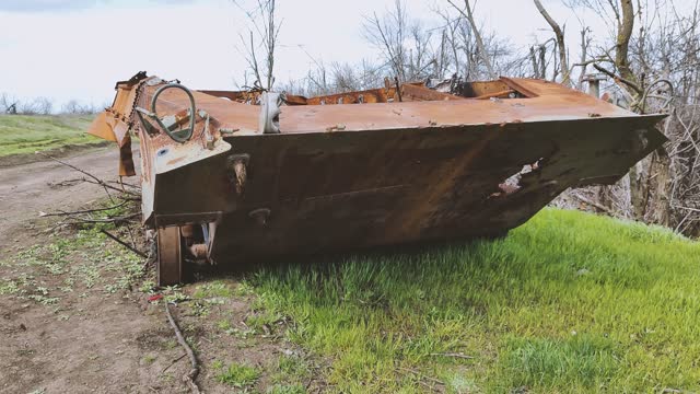 Russian tank or bmp destroyed by the Ukrainian military during the invasion of Ukraine. The remains of a blown up Russian tank in the Kherson region, Ukraine 2022 - 2023. The tank is covered with rust and begins to overgrow with plants.