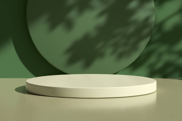 istock Glossy round podium on table counter with natural light and leaf shadows on the green wall. 1482760478