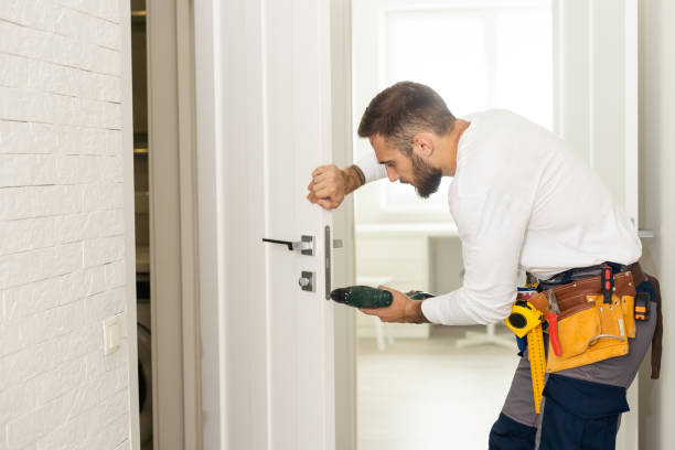 good looking man working as handyman and fixing a door lock in a house entrance stock photo