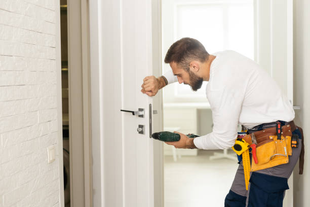 homem de boa aparência trabalhando como faz-tudo e consertando uma fechadura de porta na entrada de uma casa - home improvement drill house repairing - fotografias e filmes do acervo