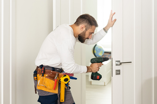High Angle View Of Male Carpenter With Screwdriver Fixing Door Lock.