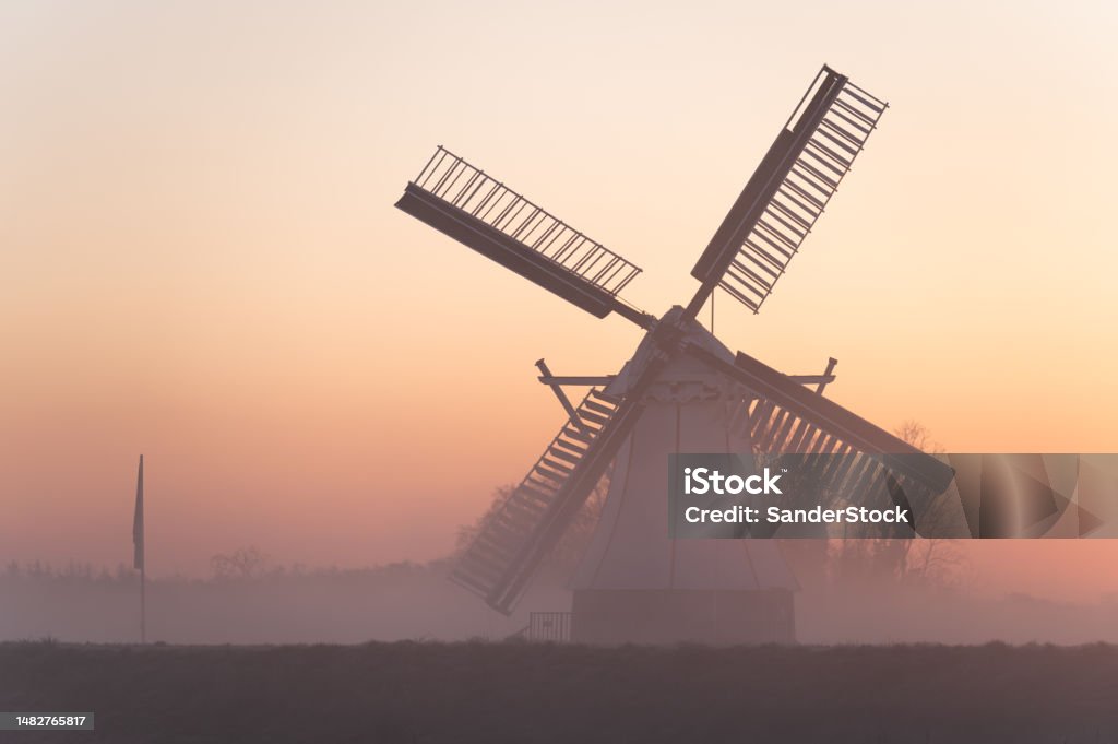 Dutch windmill Foggy, spring dawn in the Dutch countryside near a windmill. Agriculture Stock Photo
