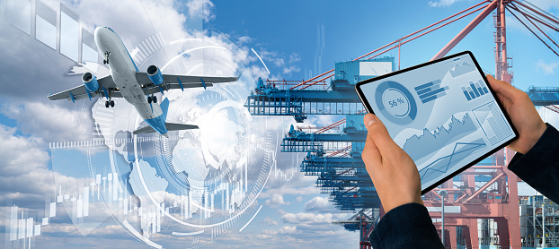 Manager with a digital tablet on a background of a ship loaded with containers in the seaport, airplane and trucks. International trade and logistics concept
