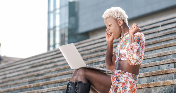 istock Transgender woman sitting on exterior steps using a laptop, remote worker 1482768393